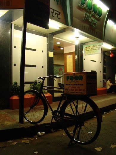 A delivery bicycle belonging to Food Plaza, take away pizzas