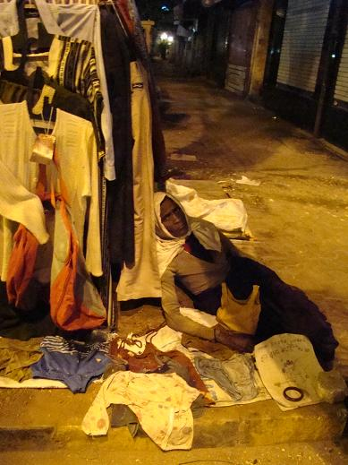 This woman lives by this tree. She sells garments, and even sleeps here. I&rsquo;ve never seen her leave. 