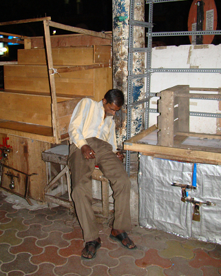 With his stock locked away, this street trader takes no chances and sleeps on a stool next to his wares.