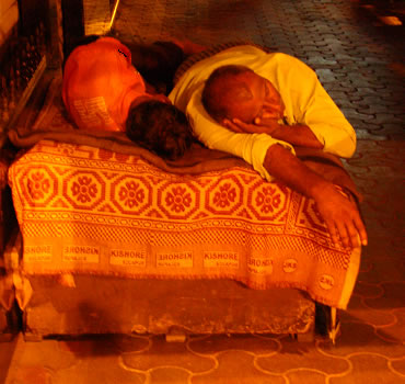 The habit is not confined to the young, some shopkeepers prefer it. In 30 degrees heat, Bombay is easy to sleep at night. This man and wife sleep on a bed they drag out of a store backroom each night to also keep gurad of their shop front.